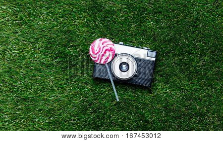 Vintage Camera And Lollipop Candy On Green Grass Background