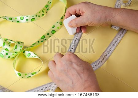 Tailor hands working with yellow fabric. Selective focus