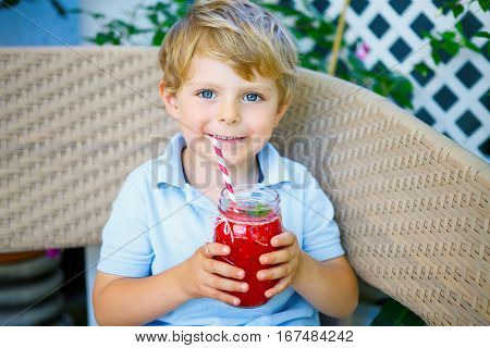 Adorable little kid boy drinking healthy fruits and vegetables juice smoothie in summer. Happy child enjoying organic drnk.