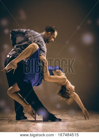 A man and a woman dancing argentinian tango on gray studio background