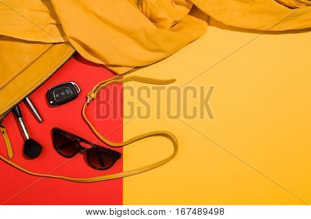 Woman's accessories flat lay on colorful background. Top view. Red and yellow pastel colors with copy space around products. Horizontal image or photograph.