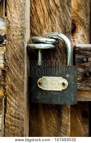 Padlock securing a wooden door to a cottage in the field.