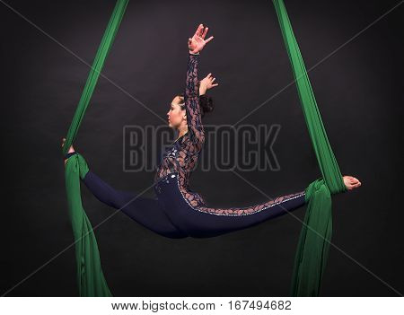 Girl's aerial acrobatics in the paintings - dark background. Studio photography of circus performers