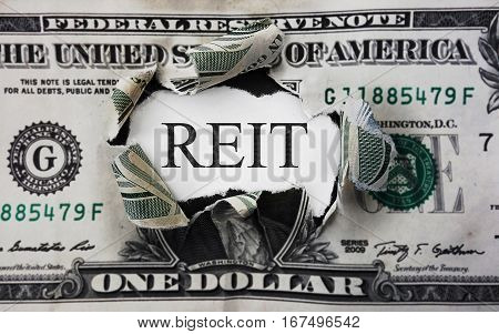 Torn dollar with REIT (Real Estate Investment Trust) paper message