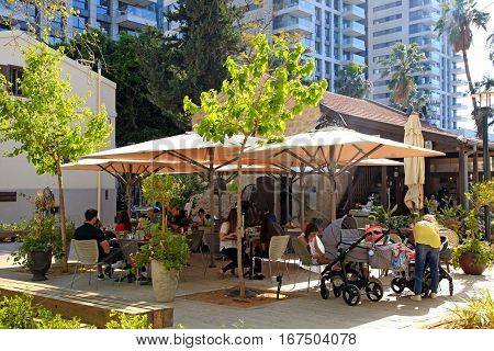 TEL AVIV, ISRAEL - APRIL 7, 2016: People rest in outdoor cafe in the modern open air commercial center and park Sarona, Tel Aviv, Israel