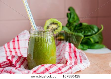 Homemade Healthy Green Smoothie With Spinach And Kiwi In A Jar Mug With A Straws On A Checkered Napk