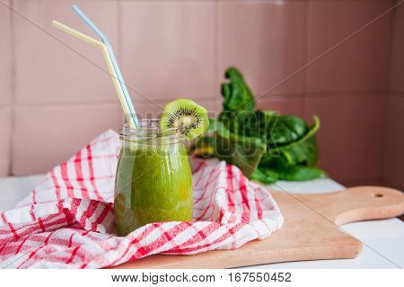 Homemade Healthy Green Smoothie With Spinach And Kiwi In A Jar Mug With A Straws On A Checkered Napk