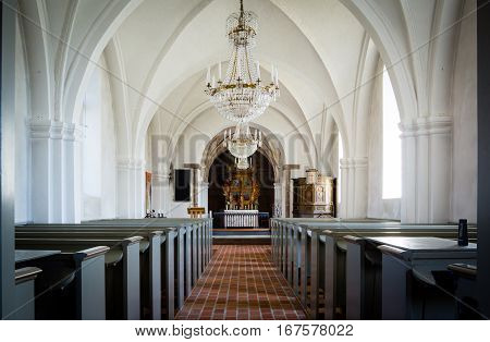 Inside a white church in the countryside with an aisle of bricks chandeliers and reredos of wood Lackalanga Sweden - May 6 2015