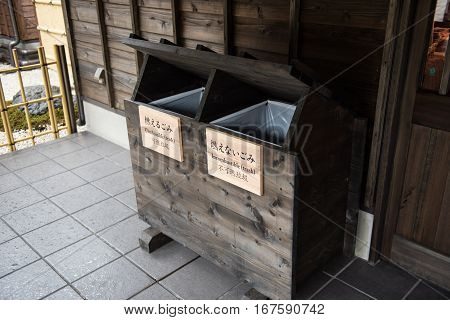 A wooden trash box kept outside a restaurant in the city of Tokyo. It has couple seperate boxes, one for combustible trashes and the other for incombustible trashes.