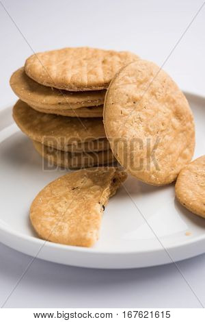 spicy fried mathri or mathari which is an indian snack served with a cup of tea, selective focus