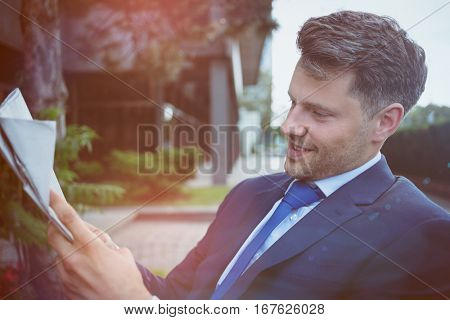 Close up of handsome businessman reading newspaper