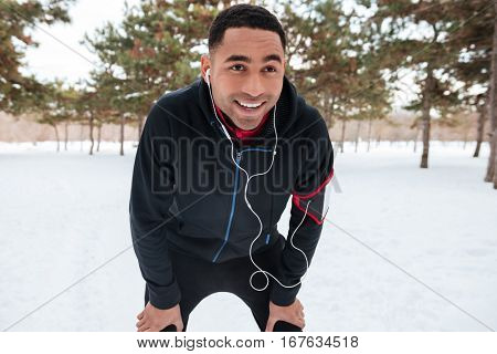 Portrait of a smiling african athlete having a break after running outdoors in winter