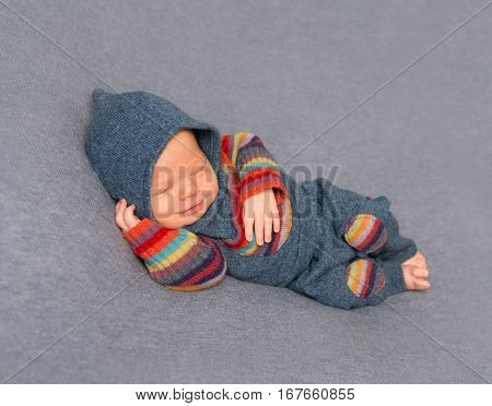 Frowning aborable kid in a bright outfit with his hand under his head, sleeping