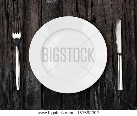 white empty dinner plate setting on old dark wooden table