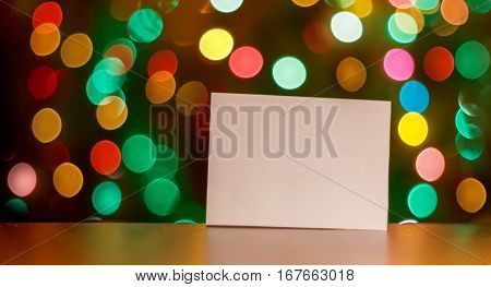 Sheet of paper with place for your text design concept on a table with christmas light bokeh as background