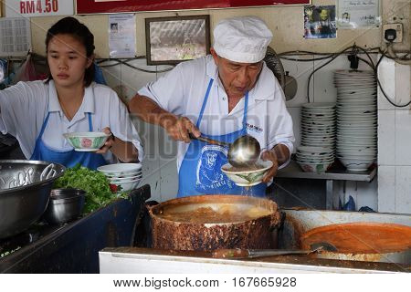 Hawker Vendor At Their Assam Laksa Noodle Stall In Air Itam, Penang