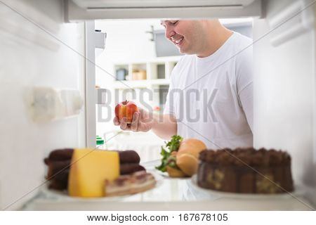 Fat man on diet make right choice and take apple from fridge