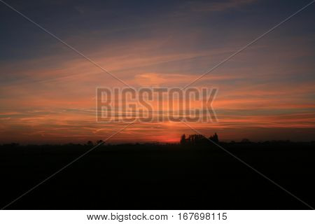 zonsondergang met heel veel kleurschakeringen en silhouet van bos