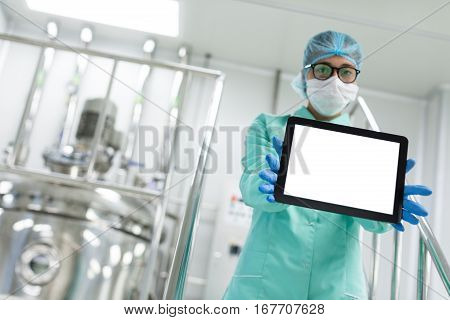 holding tablet in front scientist stand on metal stairs tank on background