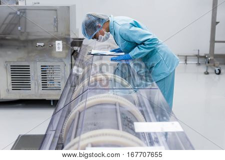 scientist woman is looking in machine in chemical factory