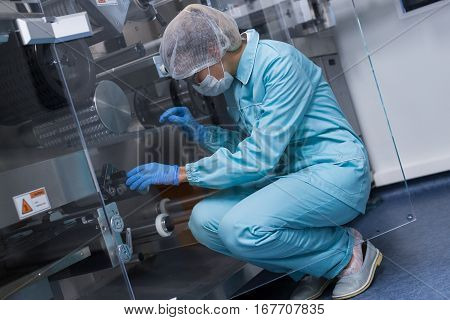 Scientist Sitting On Knees And Checking Machine