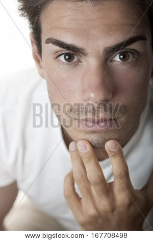 Close portrait of a handsome young man thinking with hand under chin