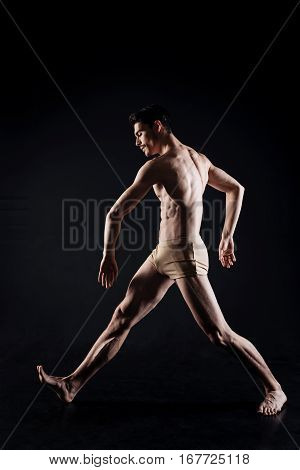 Acting in progress. Talented charismatic skilled performer standing in the studio and expressing his talent while performing against black background