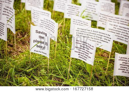 ROTTERDAM THE NETHERLANDS - AUGUST 23 2014: Art instalation in Rotterdam. Lots of tiny banners with qoutes about nature are thrust into green lawn. Save the planet concept