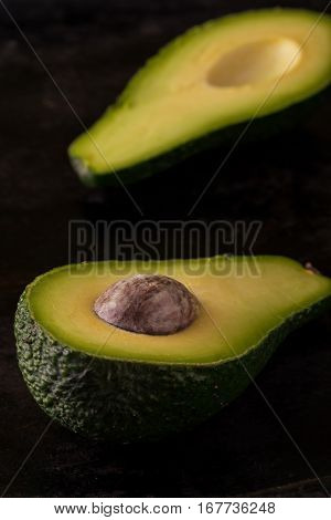 Single Avocado Severed In Half On Dark Tray