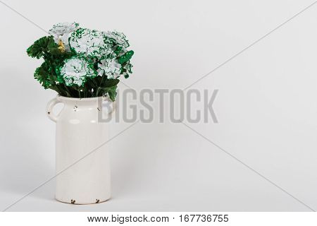 Green and white carnations in a white vintage vase