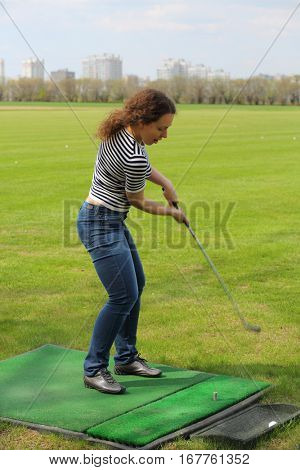 Young woman is hitting by cammock ball for golf from artificial lawn