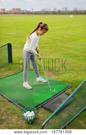 Girl with cammock traines of hit in green golf course at spring day