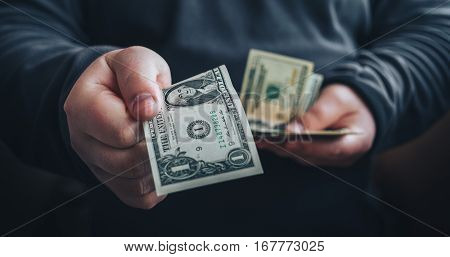 Man giving one us dollar banknote and holding cash in hands. Toned picture. Horizontal image