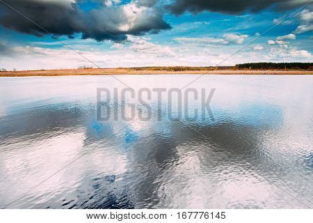 River Or Lake Landscape With Reflections Of Cloudy Sky In Water. Ripple Surface Of Calm Water At Evening Or Morning Time. Forest On Other Side. Nature Of Eastern Europe