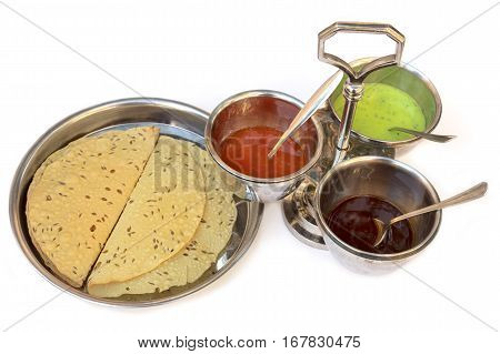 Indian bread served with the traditional assortment of sauces, in the typical tableware, on a white background