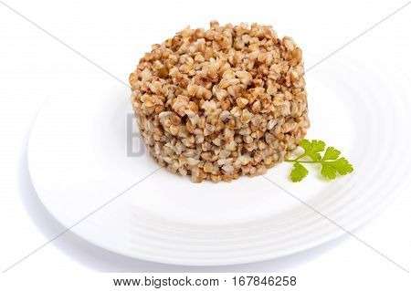 Buckwheat porridge in the form of a circle on a white plate on a white background. Dietary vegan Lenten dish. Isolate object.