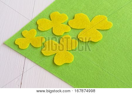 Handmade yellow felt flower sewing kit on the green felt and white wooden background
