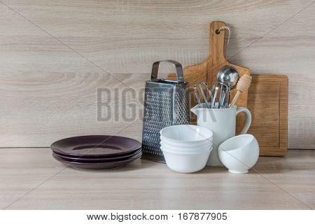 Crockery tableware utensils and other different stuff on wooden table-top. Kitchen still life as background for design. Image with copy space.