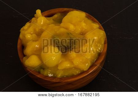 Piccalilli relish in a wooden bowl on a dark slate background.