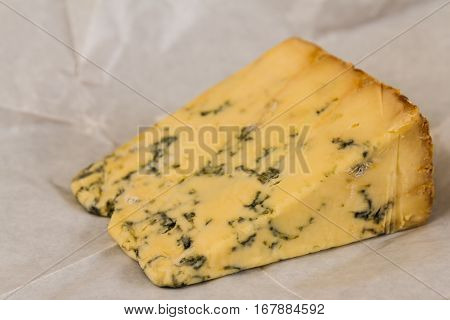 stilton cheese resting on unwrapped greaseproof paper.