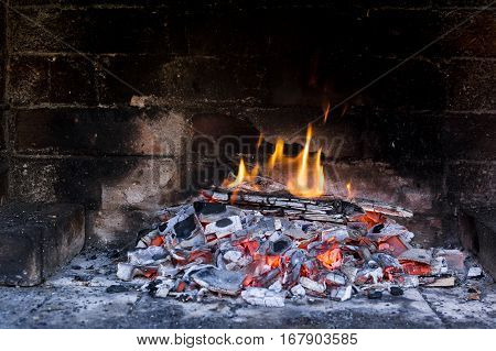 Little fire burning over pile of red hot coal and wood pieces