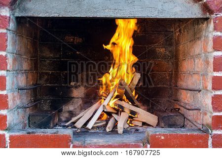 Fire just started with wooden planks inside outdoor barbecue with red bricks
