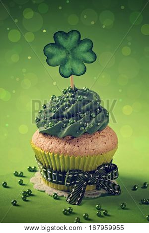 Cupcake with clover cakepick on a wooden background