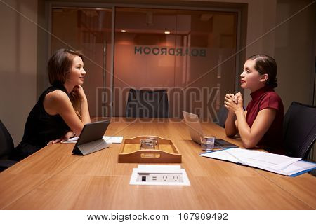 Two businesswomen working late sitting opposite each other