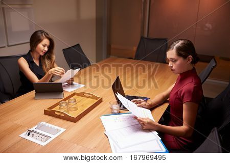 Two businesswomen doing paperwork late in an office