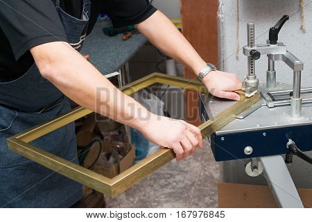 Craftsman working on frame in frameshop. Professional framer hand holding frame angle. Top view.
