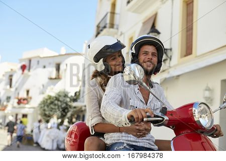 Young adult couple on a motor scooter in a street, Ibiza