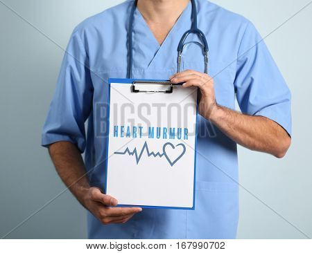 Cardiology and health care concept. Doctor's hands holding clipboard with text HEART MURMUR