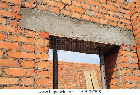 Building house construction. Window door concrete lintel with iron bar on brick unfinished house construction.