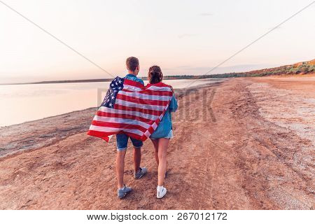 American Couple Covered In American Flag Walking On Beach
